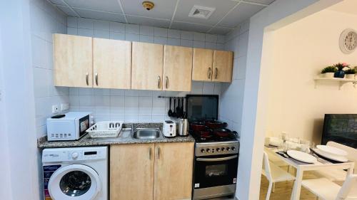 a kitchen with a stove and a washer and dryer at Spacious Furnished studio with balcony Spain cluster International city in Dubai