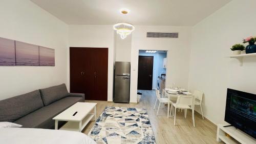 a living room with a couch and a table at Spacious Furnished studio with balcony Spain cluster International city in Dubai
