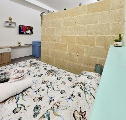 a bedroom with a bed and a brick wall at Aquamarina Rooms in Porto Cesareo