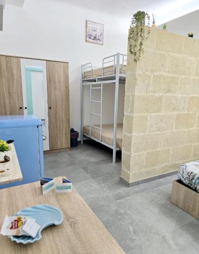 a room with a bunk bed and a brick wall at Aquamarina Rooms in Porto Cesareo