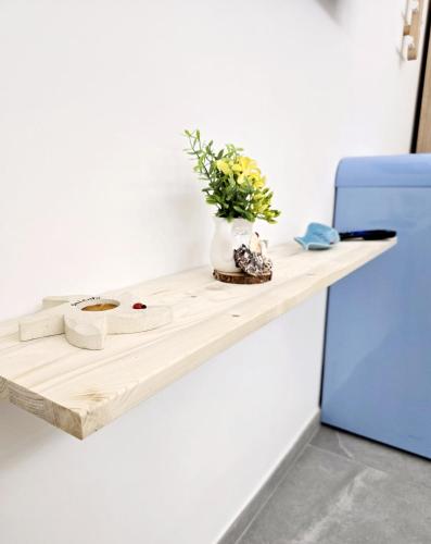a wooden shelf with a vase of flowers and a blue refrigerator at Aquamarina Rooms in Porto Cesareo
