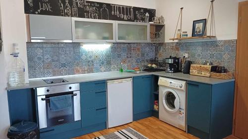 a kitchen with blue cabinets and a washing machine at Апартамент в Oasis Beach Kamchia -THE FAVOURITE BLUE in Bliznatsi