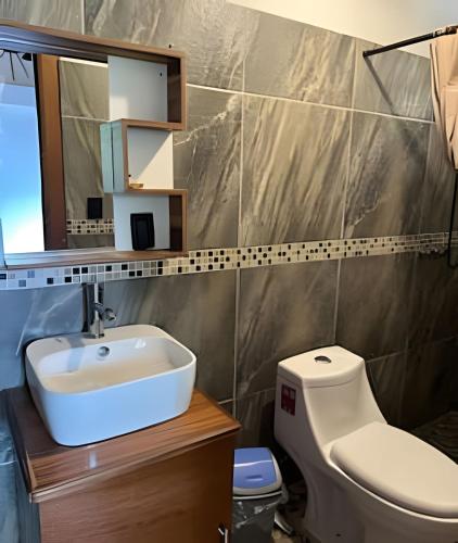 a bathroom with a sink and a toilet and a mirror at Casa Las Palmas Playa La Saladita in Zihuatanejo