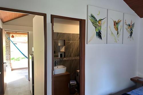 a bathroom with paintings of birds on the wall at Casa Las Palmas Playa La Saladita in Zihuatanejo