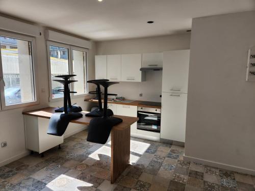 - une cuisine avec des placards blancs et des chaises noires dans l'établissement T3 Cosy, à Saint-Étienne