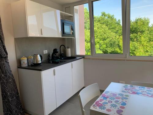 a kitchen with white cabinets and a table and window at Casa Armonia Apartment Sulmona in Sulmona