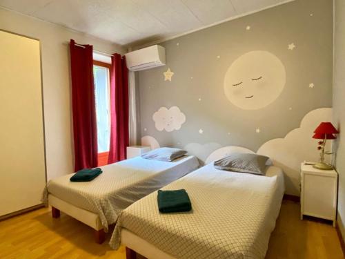 deux lits dans une chambre avec une fresque de lune sur le mur dans l'établissement Appartement Cité de Carcassonne, à Carcassonne