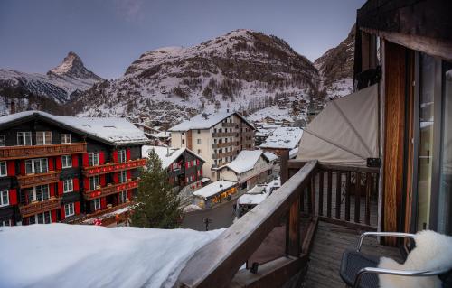 a view from a balcony of a town with snow covered mountains at Hotel Bellerive in Zermatt