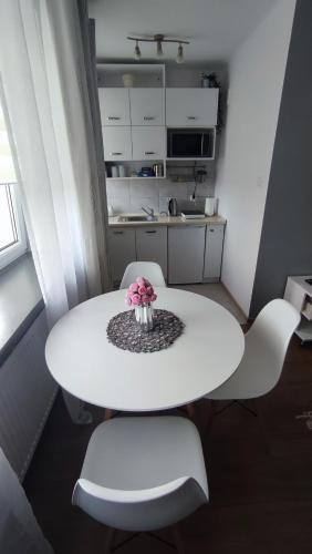 a white table with two chairs and a vase of flowers on it at Apartamenty Urban Concept in Zamość