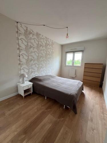une chambre avec un grand lit et un parquet dans l'établissement Jolie maison paisible, à Gujan-Mestras