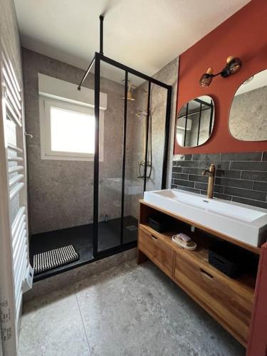 La salle de bains est pourvue d'une douche et d'un lavabo blanc. dans l'établissement Jolie maison paisible, à Gujan-Mestras