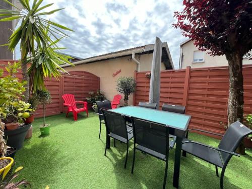 a patio with a table and chairs on the grass at Jolie maison paisible in Gujan-Mestras