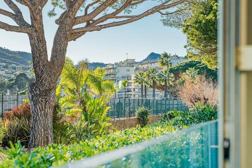- une vue sur un arbre et un bâtiment dans l'établissement Appartement pied dans l'eau, à Mandelieu-la-Napoule