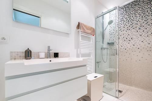 une salle de bain blanche avec un lavabo et une douche dans l'établissement Appartement pied dans l'eau, à Mandelieu-la-Napoule