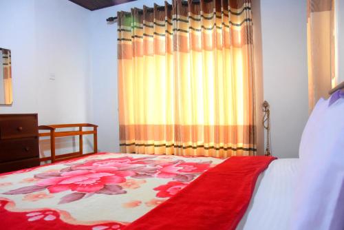a bedroom with a bed and a curtain with flowers on it at Train View Villa in Nanu Oya