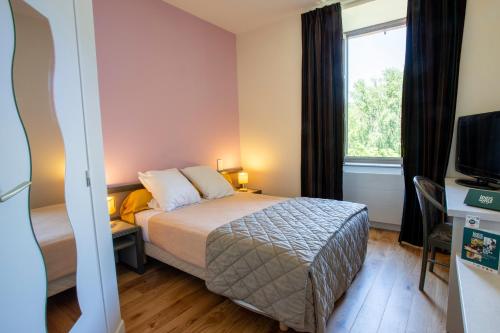 a hotel room with a bed and a window at Logis Hôtels - Hostellerie des Lauriers - Hôtel et Restaurant in Alban