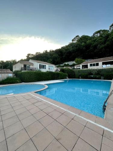 une grande piscine bleue devant une maison dans l'établissement L'Esmeralda - Maisonnette de vacances, à Villeneuve-Loubet