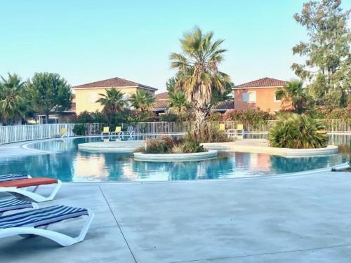 une piscine avec deux chaises et des palmiers dans l'établissement Maison Vacances au Domaine de Golf Piscine, à Fabrègues