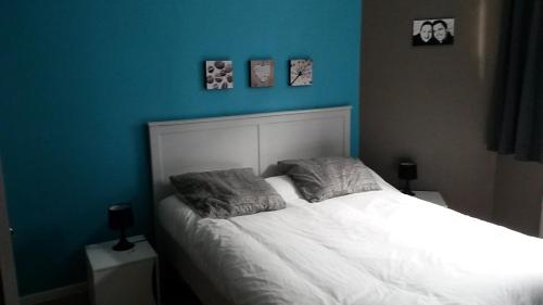 une chambre avec un lit blanc avec un mur bleu dans l'établissement Bel appartement T2 bis à deux pas de l'hypercentre, à Toulouse