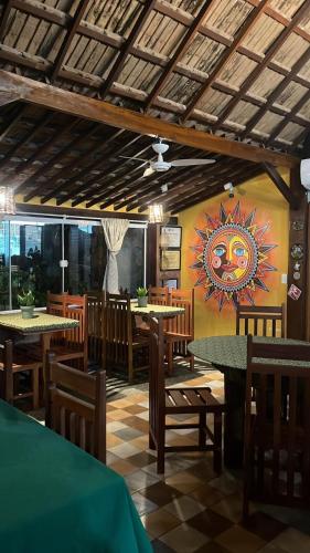 a restaurant with tables and chairs and a painting on the wall at Pontal dos Sonhos- Chalés Praia do Farol in Coruripe