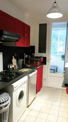 - une cuisine avec des placards rouges et un lave-linge dans l'établissement Bel appartement T2 bis à deux pas de l'hypercentre, à Toulouse