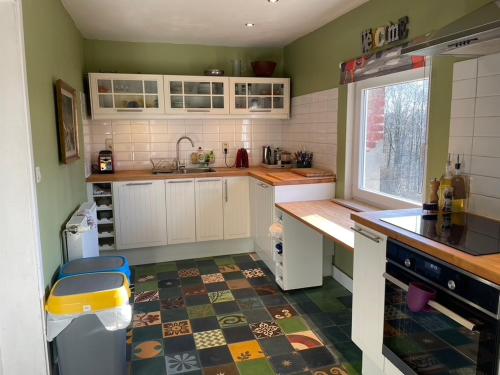 a kitchen with white cabinets and a tile floor at La Bruyere du Coq Stables in Sart-Dames-Avelines