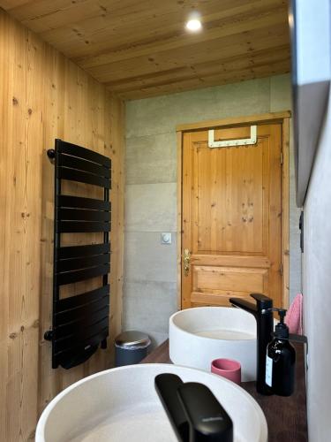 La salle de bains est pourvue d'un lavabo et d'un mur en bois. dans l'établissement Chalet dans un écrin de verdure avec SPA privatif, à Jeanménil