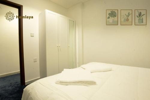a bedroom with a white bed and a mirror at hamlaya apartments هملايا للشقق الفندقيها لفروانيه in Kuwait