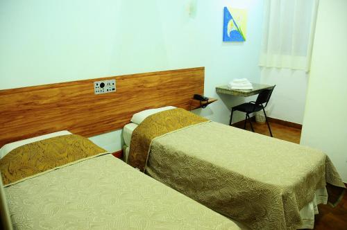 a hotel room with two beds and a table at Hotel Pouso Novo in Matão