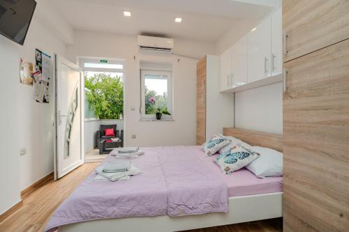 ein Schlafzimmer mit einem großen Bett mit einer lila Decke in der Unterkunft Apartmani DALI in Novalja