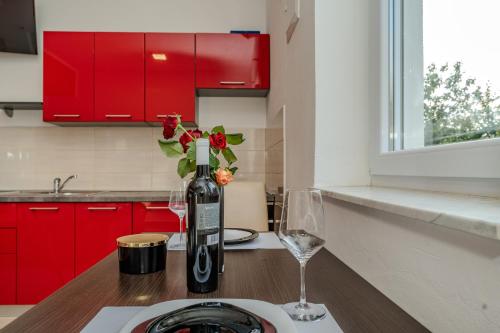 ein Tisch mit einer Flasche Wein und zwei Gläsern in der Unterkunft Apartmani DALI in Novalja