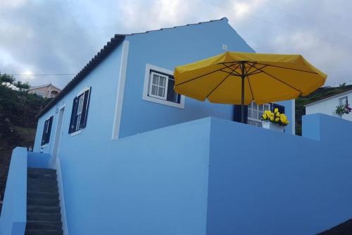 a blue house with a yellow umbrella and stairs at Sunrise House in Companhia de Baixo