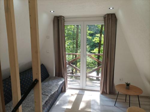 a living room with a couch and a large window at Planinska vila KTM Lisine in Despotovac