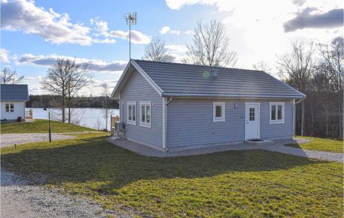 a small house on a grassy yard with a building at Awesome Home In Backaryd in Backaryd