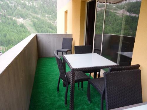 d'une table et de chaises sur un balcon avec de l'herbe verte dans l'établissement Appartement de 3 pièces au centre d'Isola 2000, parking, proche pistes - FR-1-292-210, à Isola