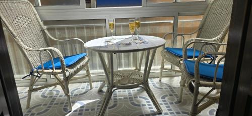 a table with two chairs and two glasses of champagne at Casa de la Felicidad cerca de la playa in Santa Pola