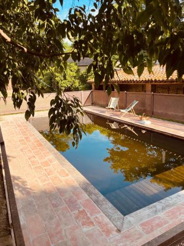 une mare d'eau sur une allée en briques à côté d'une maison dans l'établissement Gîte de charme du Domaine Pagnon Frigoulette, à Torreilles