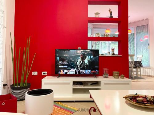 ein Wohnzimmer mit einem TV an einer roten Wand in der Unterkunft Lalëz AZURE Villa - 3 Bedrooms in Lalzit Bay