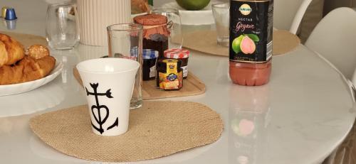 une table blanche avec une tasse et une assiette de nourriture dans l'établissement Domino 1 Superbement rénové - 2 chambres - Terrasse à 300m plage commerces, au Grau-du-Roi