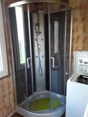 une douche avec une porte en verre à côté d'un lave-linge dans l'établissement pavillon indépendant, à Bondy