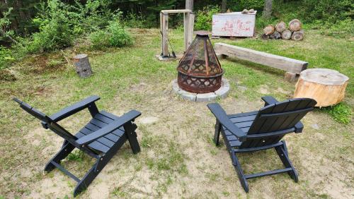 two black chairs and a grill in a yard at Chalet des Sources SPA Gazebo panoramique in Mont-Blanc