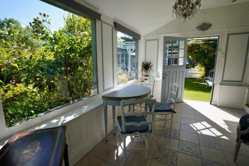 une véranda avec une table et des chaises dans l'établissement Maison charmante avec jacuzzi et cours d'eau, à Courtonne-la-Meurdrac