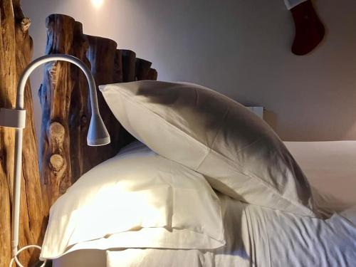 a bed with white pillows and a lamp on it at Casita Rural de Campo con Jardín Privado in El Berrueco