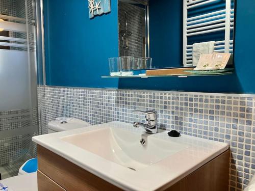 a bathroom with a white sink and a blue wall at Casita Rural de Campo con Jardín Privado in El Berrueco