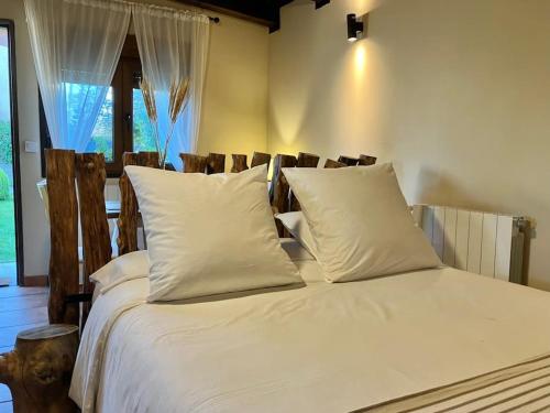a bed with white sheets and pillows in a room at Casita Rural de Campo con Jardín Privado in El Berrueco