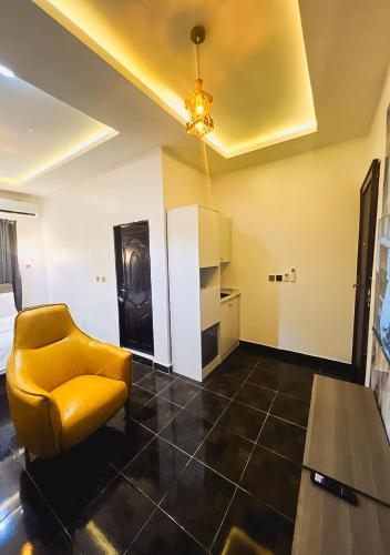a living room with a yellow chair in a room at Kam Apartment and Taverns in Abuja