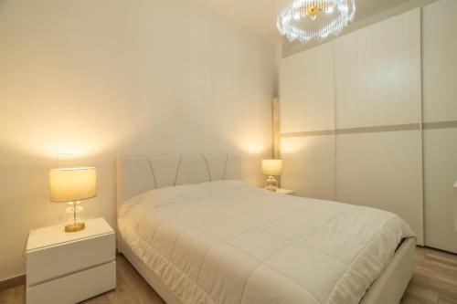 a white bedroom with a white bed and two lamps at La Casa di Girolamo e Irene in Lampedusa