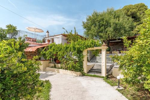 a house with stairs and an umbrella in front of it at Pefkos Cottage in Panormos Skopelos