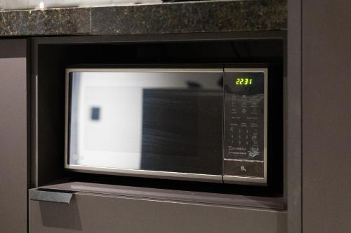 a microwave oven with the clock on it at TOLIVE One Housi Recife by Carpediem in Recife