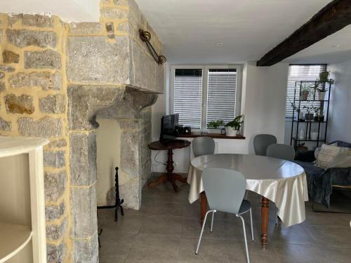 - un salon avec une table et une cheminée en pierre dans l'établissement 3 Rue des Caux, à Sainte-Marie-du-Mont